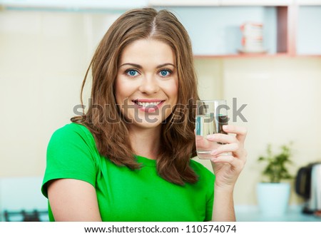 Close up portrait of Young Woman drinking water at home interior. Clothes of green color.