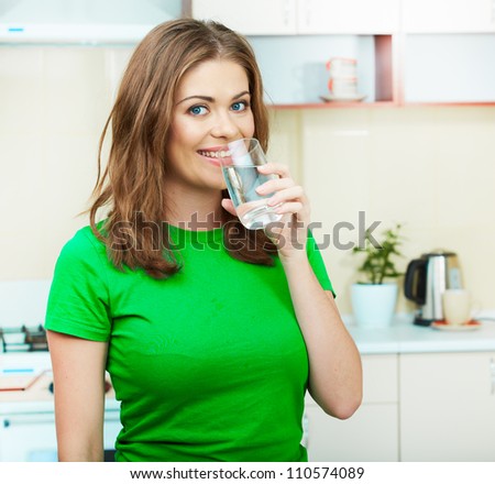 Young woman drinking water at home interior. Clothes of green color.
