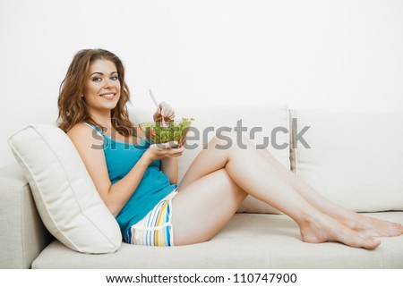 Young woman with long hair sitting  on sofa at home and eating healthy food.