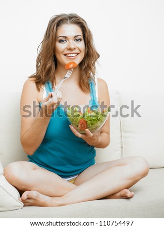 Young woman with long hair sitting  on sofa at home and eating healthy food.