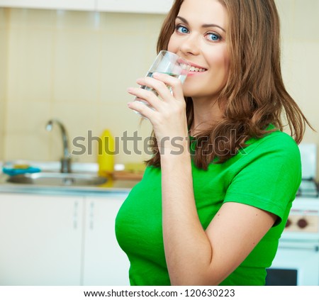 Close up portrait of Young Woman drinking water at home interior. Clothes of green color.