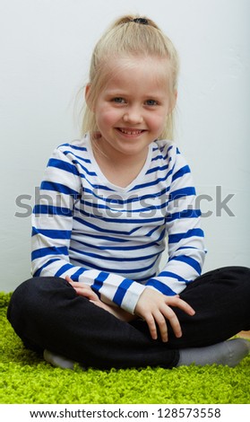 Kid girl seat on green  floor.  isolated portrait.