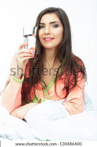 Woman drink water seating in bed. Female smiling model .