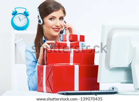 Smiling operator seat at table with red gift box. Happy business woman at office. Female business model posing.