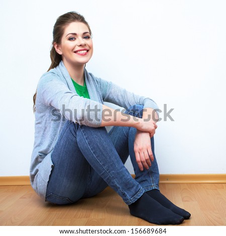 Woman natural portrait. Smiling girl seat on a floor. White background isolated.