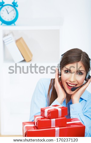 Smiling operator seat at table with red gift box. Happy business woman at office. Female business model posing.