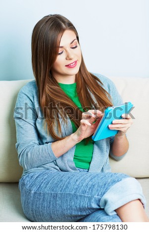Smiling woman on sofa with tablet pc. Young smiling model portrait.