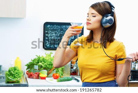 Woman cooking with fun. Girl drinking juice in kitchen and listen music.