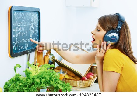 Woman in kitchen show on menu board. Cooking fun with music.