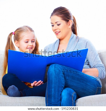 Preparation for s?hcool at home with book. Mother , daughter sitting on sofa, reding book.