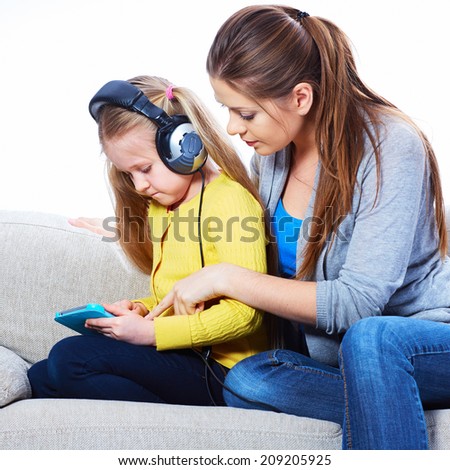 Girl listening lesson with tablet pc and headphones with mother.