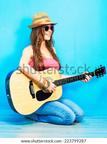 Music woman portrait with guitar. Blue background.