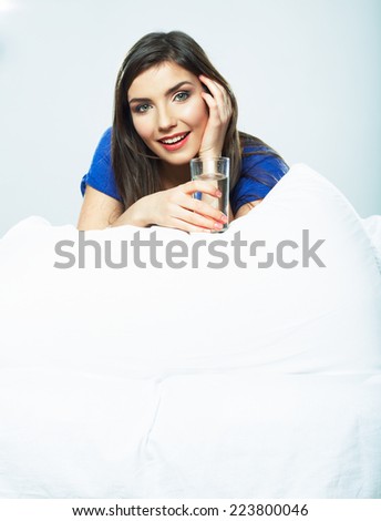 Young Woman in bed holding water glass. Smiling model.