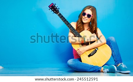girl with guitar against blue . hipster style portrait of young woman .