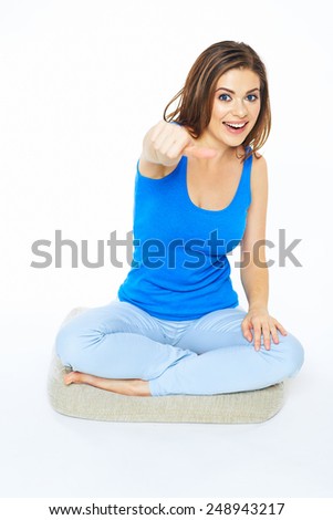 Smiling woman sitting on floor in yoga pose . Thumb up. White background isolated.