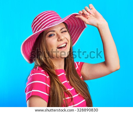 Woman winking. Portrait of smiling woman standing against blue background touching his hat. Long hair of young female model.