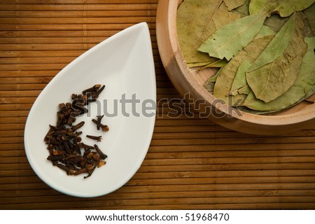 White ceramic dish and wooden dish with spices on the kitchen wood litter, bamboo strips.