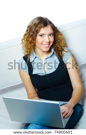 Young smiling woman sitting with  laptop on a couch. Indoor female portrait