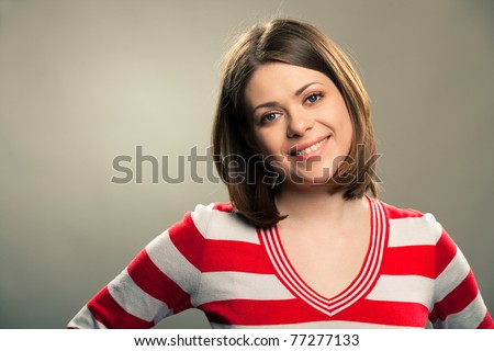 Close-up portrait of young happy woman , big natural smile, beautiful model posing in studio over gray background . Isolated on gray. Light make-up
