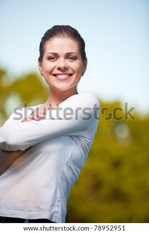 Woman on summer sky and tree background. Outdoor portrait with big smile.