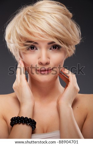 Young woman portrait. Closeup beauty studio shoot. Healthy clean skin and perfect makeup on beautiful face of white model with short blonde hair. Beautiful girl. Posing fashion model.