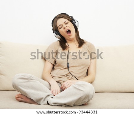 young girl portrait sitting  on a sofa, listen music in headphones. indoor relax at home.