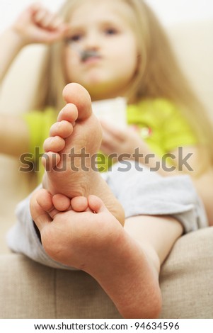 little girl eats vegetarian meal,  sitting on sofa with foot