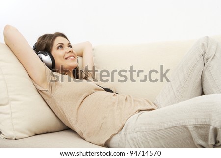 young girl portrait lying on a sofa, listen music in headphones. indoor relax at home. beautiful woman. smiling and happy