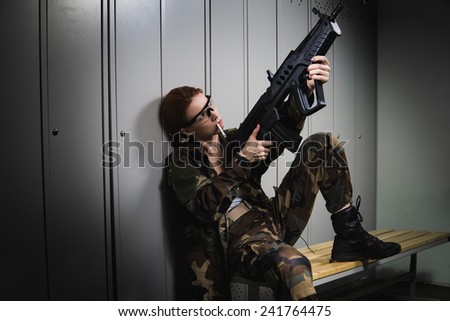 A shoot of young caucasian beautiful redhead woman sitting on the bench at locker room. Ã?Â�Ã?Â¡hecking weapon.