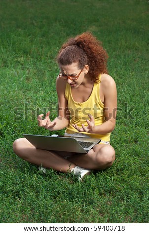 Young woman sitting cross-legged with laptop on her lap,  frustrated