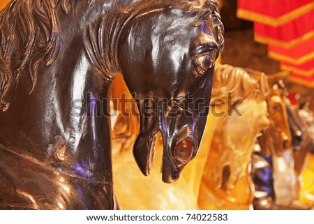 Foreground of the head of a wooden horse, wooden horses in the background color