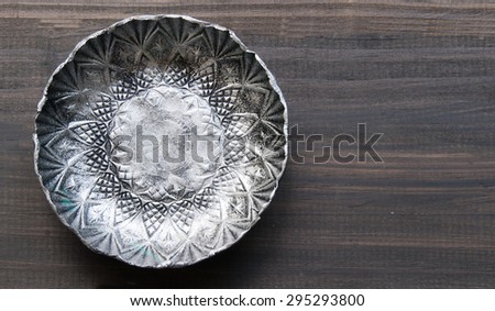small textured metal plate on a wooden black background