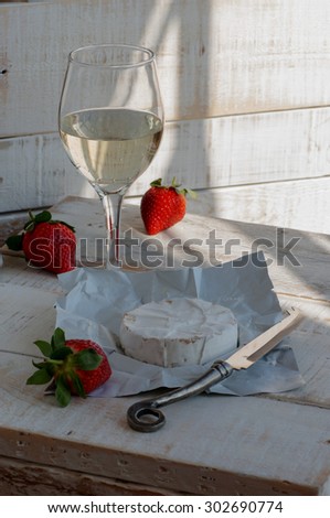 glass of wine, cheese and strawberries on the wooden table
