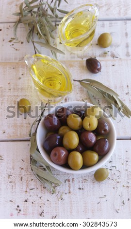 black and green olives and olive oil on a white wooden table, rustic, macro