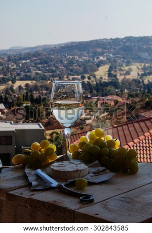 glass of wine on a background of mountains with cheese and grapes