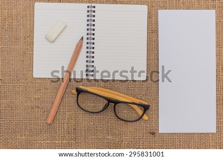 note book ,pencils,eraser,glasses,envelope on sack background