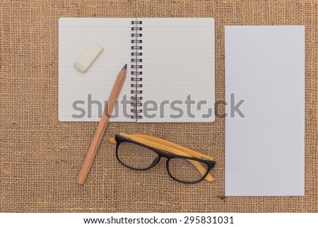 note book ,pencils,eraser,glasses,envelope on sack background