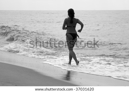 Woman jogging at the beach, black and white