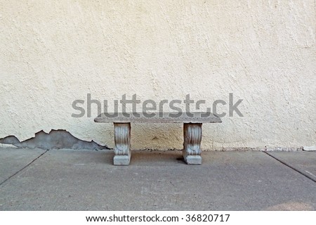 Solitary concrete bench against stucco wall