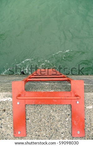 Orange metal safety ladder on concrete breakwater