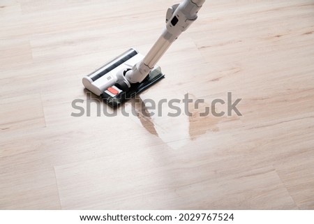 Modern vacuum cordless vacuum cleaner with water nozzle for cleaning floors. Close-up of vacuum cleaner and damp footprint on floor. House cleaning.