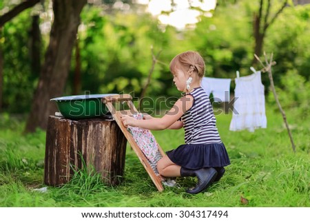 little helper girl washes white dress in a basin using the washboard outdoors
