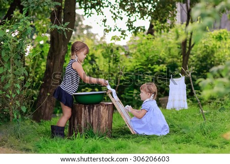 little helper girls washes white dress in a basin outdoors using the washboard outdoors
