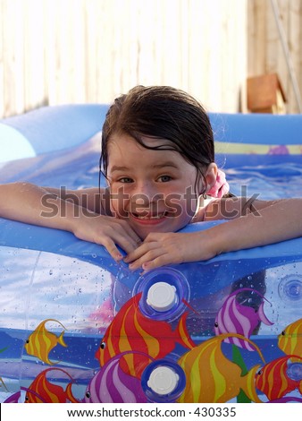 Little girl in a backyard pool and a silly smile.