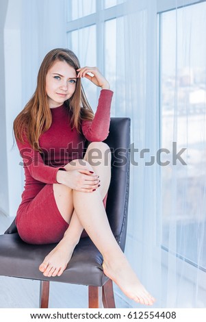 A Red Haired Girl Sits On A Chair Near A Window With Crossed Legs A Red Haired Girl Sits On A Chair Near A Window With Crossed Legs
