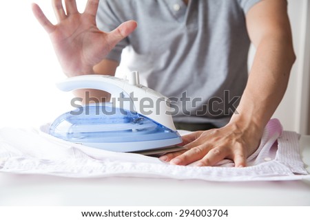 A man ironing his shirts and burning his fingers
