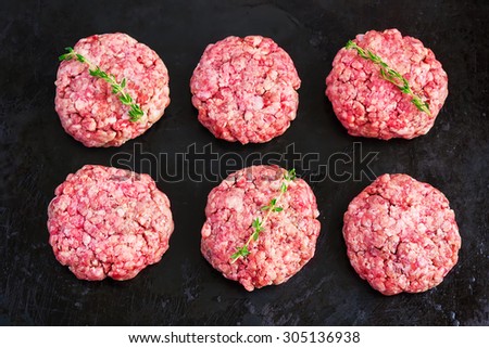 raw burgers from organic beef on black background, top view