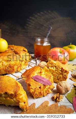 Pieces of apple pie, apples, honey and autumn leaves