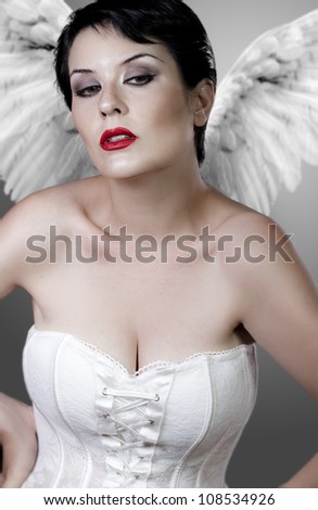 Beautiful sad angel with white corset and light wings, underwear