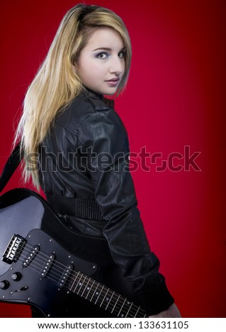 Beautiful young blonde dressed in black rock with electric guitar